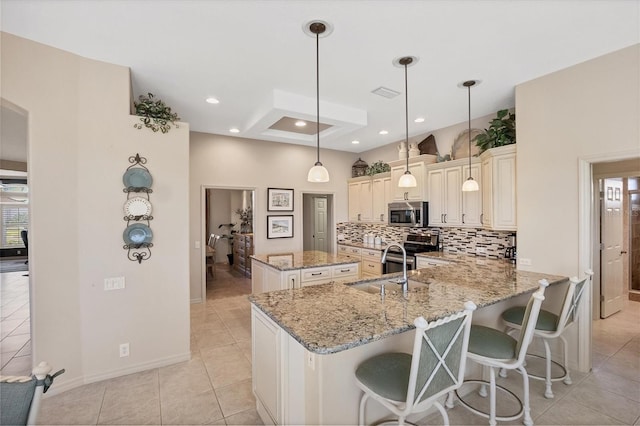 kitchen featuring appliances with stainless steel finishes, decorative backsplash, hanging light fixtures, kitchen peninsula, and light stone countertops