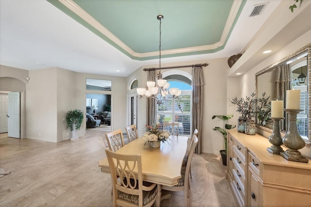 dining room featuring light wood-type flooring, an inviting chandelier, and a tray ceiling