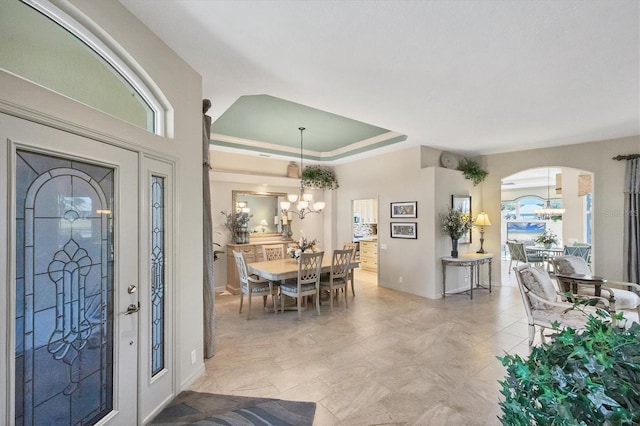 foyer entrance featuring an inviting chandelier and a raised ceiling