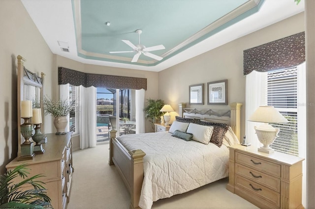 bedroom with a raised ceiling, light carpet, access to exterior, and ceiling fan