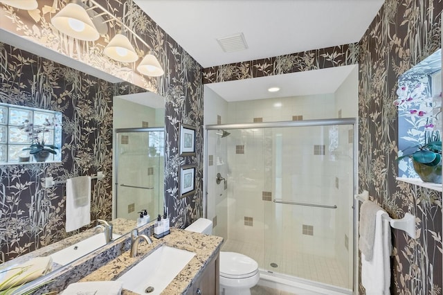 bathroom featuring vanity, a shower with shower door, and toilet