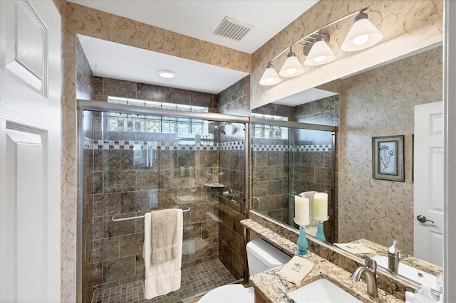 bathroom featuring vanity, toilet, and a shower with shower door