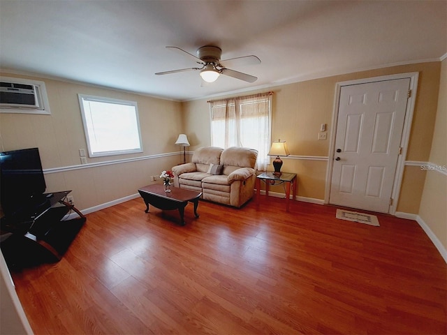 living room featuring hardwood / wood-style floors, crown molding, a wall mounted AC, and ceiling fan