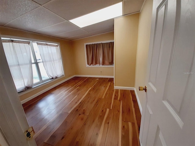 empty room featuring a paneled ceiling and light wood-type flooring