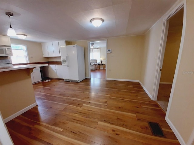 kitchen featuring decorative light fixtures, light wood-type flooring, white appliances, a healthy amount of sunlight, and white cabinets