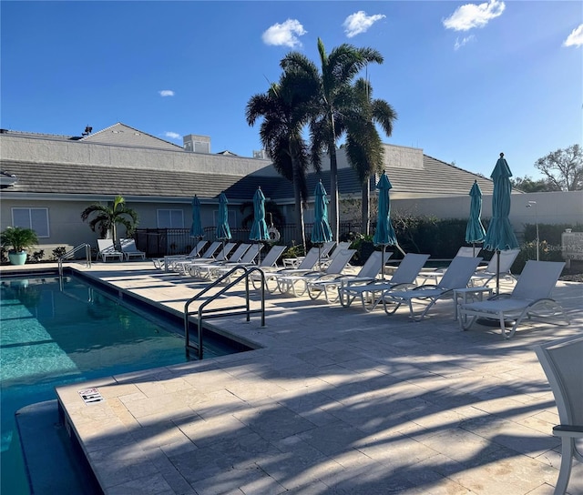 community pool with a patio area and fence