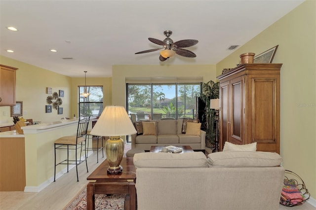 living room featuring a wealth of natural light, ceiling fan, and light hardwood / wood-style flooring