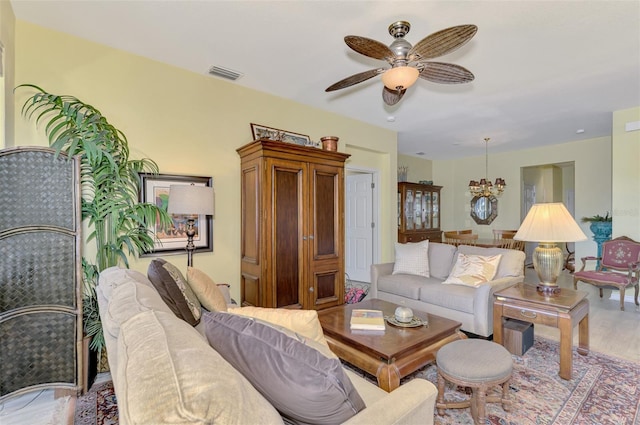 living room with ceiling fan with notable chandelier and light hardwood / wood-style flooring