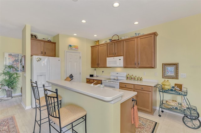 kitchen with white appliances, a breakfast bar area, and an island with sink