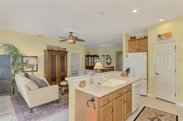 kitchen with sink, white appliances, light tile patterned floors, ceiling fan, and a center island with sink