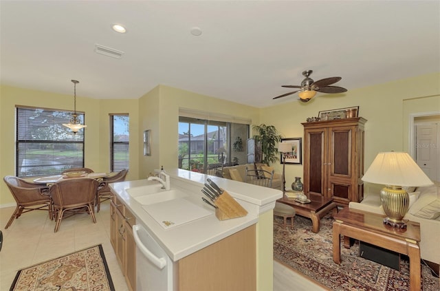 kitchen featuring light tile patterned flooring, sink, decorative light fixtures, dishwasher, and an island with sink