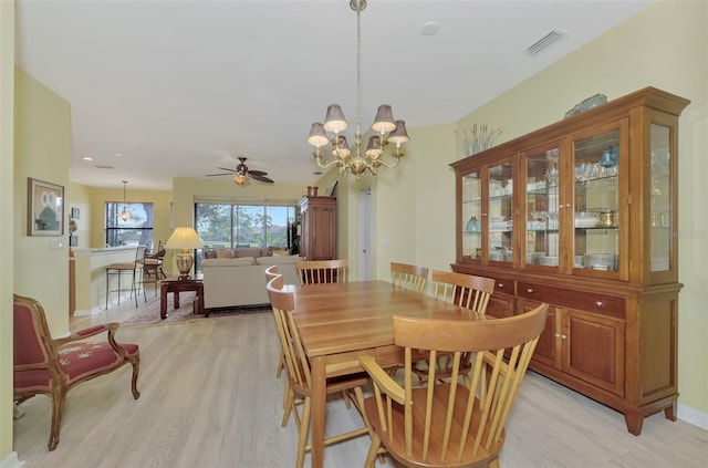 dining room with ceiling fan with notable chandelier and light wood-type flooring