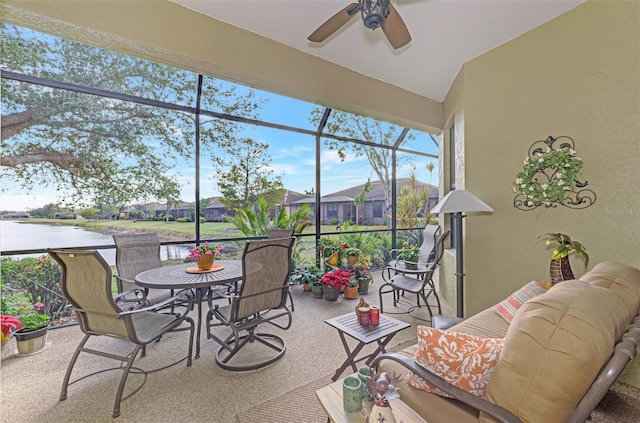 sunroom / solarium with ceiling fan and a water view