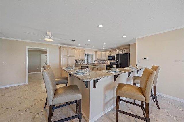 kitchen with a breakfast bar, kitchen peninsula, light tile patterned floors, and black appliances