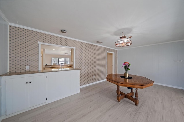 unfurnished dining area with sink, light hardwood / wood-style flooring, and ornamental molding