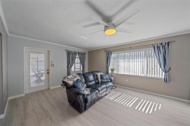 living room with a textured ceiling, ornamental molding, light hardwood / wood-style floors, and a healthy amount of sunlight