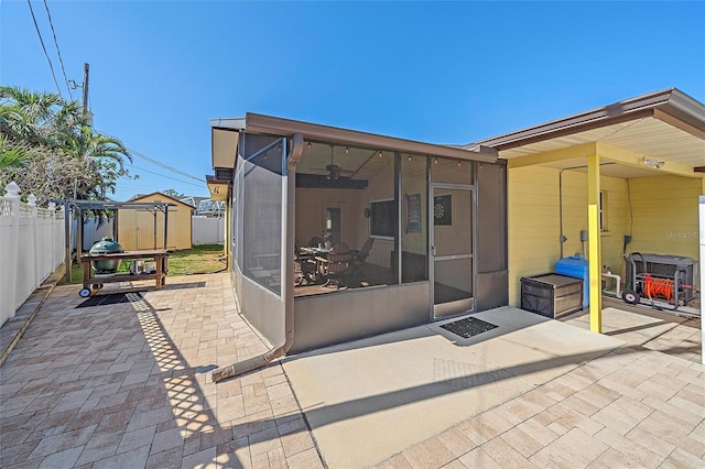 back of property featuring a sunroom, a shed, and a patio area