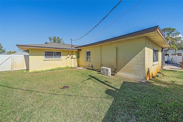 rear view of property featuring ac unit and a lawn