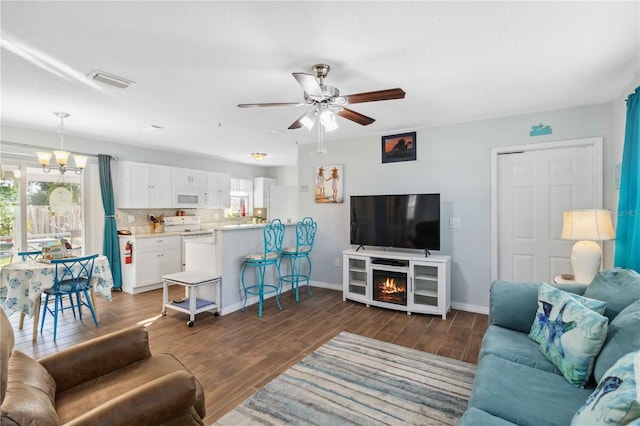 living room with dark hardwood / wood-style floors and ceiling fan with notable chandelier