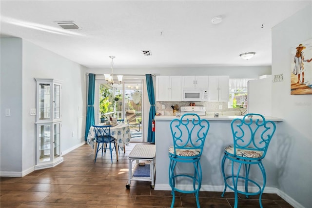 kitchen featuring decorative light fixtures, white cabinetry, backsplash, dark hardwood / wood-style flooring, and white appliances