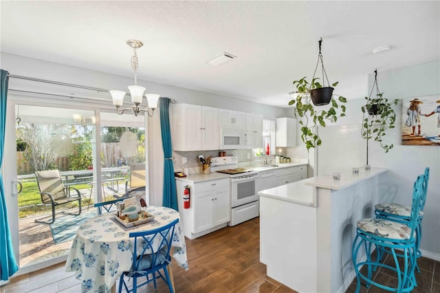 kitchen featuring white appliances, white cabinetry, backsplash, decorative light fixtures, and kitchen peninsula