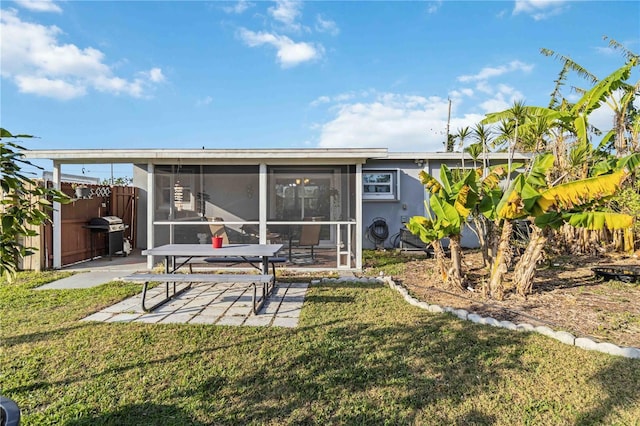 rear view of house with a yard, a patio area, and a sunroom