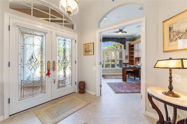 tiled entrance foyer with a chandelier and french doors