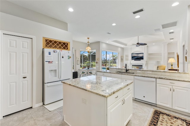 kitchen featuring light stone countertops, a center island, sink, and white appliances