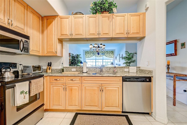 kitchen with light stone counters, appliances with stainless steel finishes, light tile patterned flooring, and sink