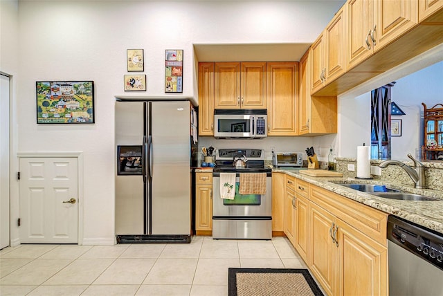 kitchen featuring sink, appliances with stainless steel finishes, light stone countertops, light tile patterned flooring, and light brown cabinets