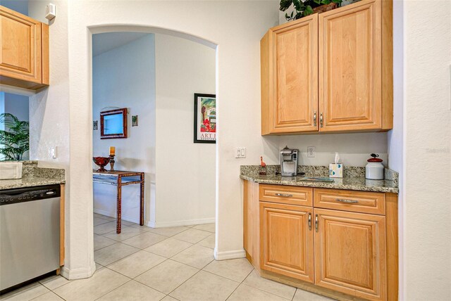 kitchen with light stone counters, light tile patterned floors, and dishwasher