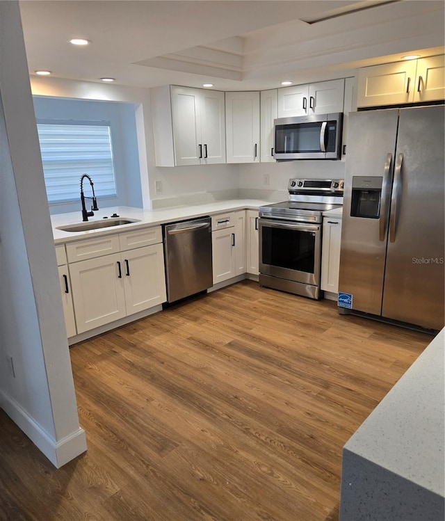 kitchen with sink, light hardwood / wood-style flooring, stainless steel appliances, and white cabinets