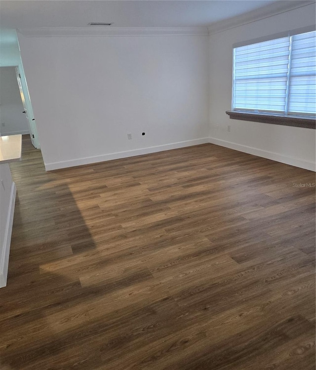 empty room with crown molding and dark wood-type flooring