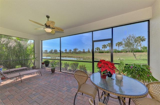 sunroom / solarium with a water view and ceiling fan