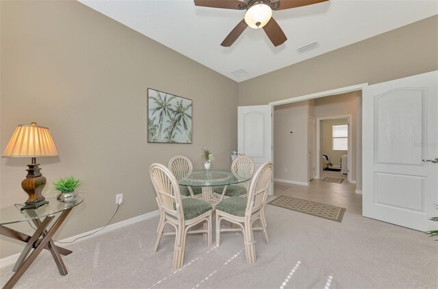 dining space featuring ceiling fan, vaulted ceiling, and light carpet