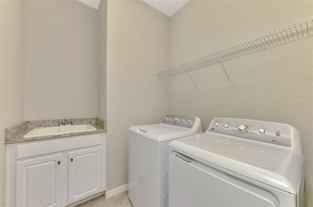 clothes washing area featuring light tile patterned flooring, washer and clothes dryer, and sink