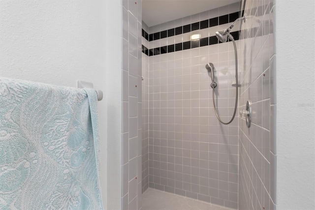 bathroom featuring a textured wall and a shower stall