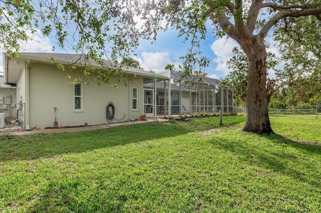 rear view of house with a yard, fence, and stucco siding