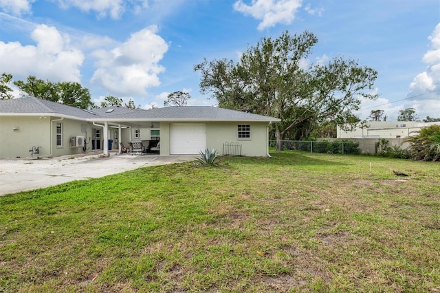 rear view of property with a lawn, concrete driveway, an attached garage, fence, and stucco siding