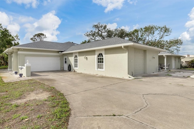 view of front of property featuring driveway, roof with shingles, an attached garage, and stucco siding