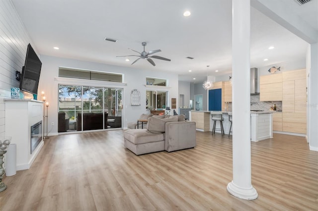 living room featuring a large fireplace, light wood-style flooring, visible vents, and recessed lighting