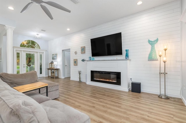 living room with ceiling fan, light wood-style flooring, recessed lighting, a glass covered fireplace, and decorative columns