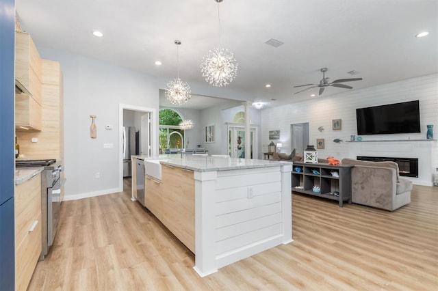 kitchen with appliances with stainless steel finishes, open floor plan, a kitchen island with sink, and decorative light fixtures