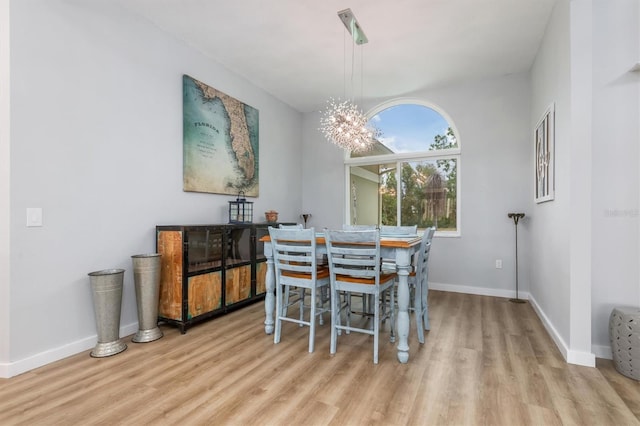 dining room featuring light wood-type flooring, an inviting chandelier, and baseboards