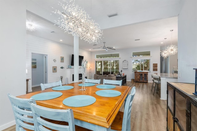 dining room with recessed lighting, ceiling fan with notable chandelier, a fireplace, visible vents, and light wood-type flooring