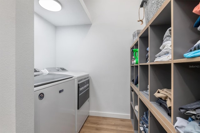 laundry area with laundry area, light wood-type flooring, independent washer and dryer, and baseboards