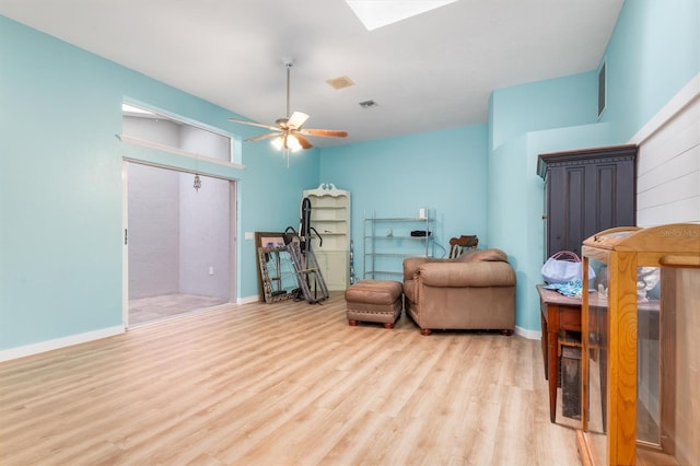 living area with ceiling fan, light wood-style flooring, a skylight, visible vents, and baseboards