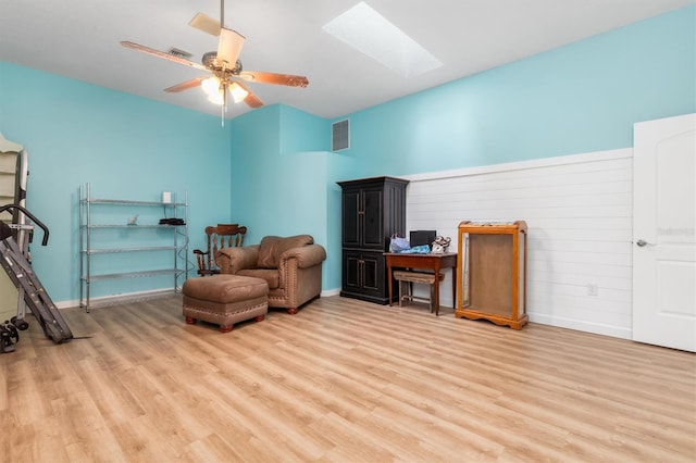 living area featuring visible vents, a skylight, light wood-style flooring, and baseboards