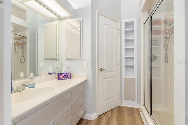 full bathroom with a stall shower, a walk in closet, wood finished floors, and vanity