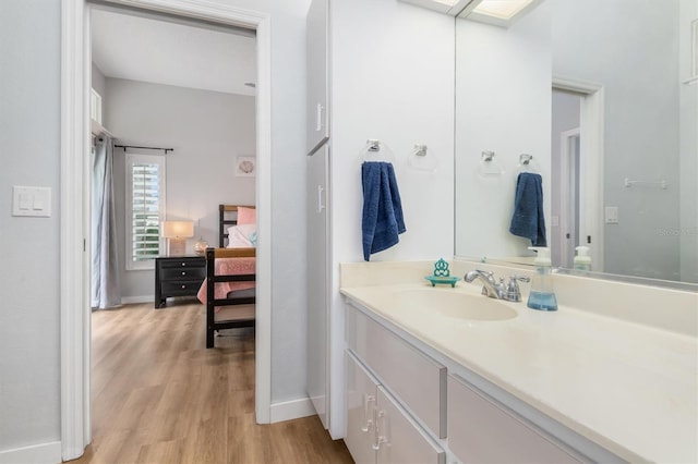 ensuite bathroom featuring baseboards, vanity, ensuite bath, and wood finished floors